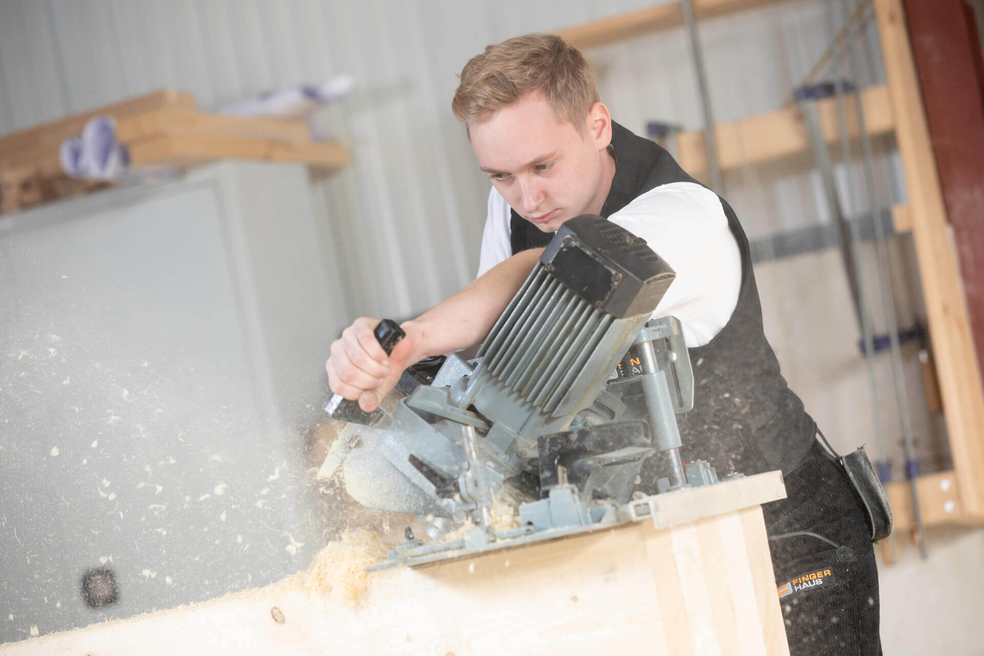 Mitarbeiter in der Produktion von FingerHaus sägt Holz